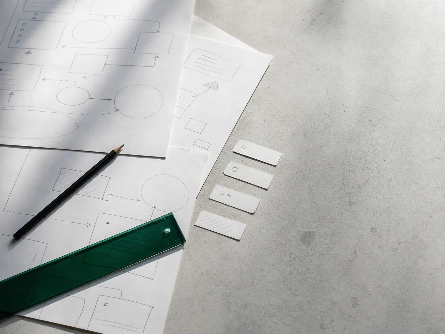 Paper process maps, graphite pencil and an emerald acrylic ruler